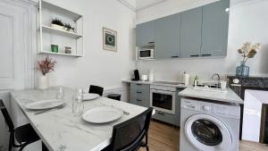 uma cozinha branca com uma mesa e uma máquina de lavar roupa em L'authentique em Autun