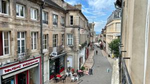 uma rua urbana vazia com edifícios, mesas e cadeiras em L'authentique em Autun