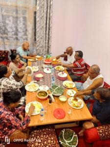 Moonshine Home stay في سريناغار: مجموعة من الناس يجلسون حول طاولة يأكلون الطعام