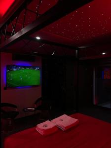 a dark room with a bed and a tv with a soccer game at Chambre Romantique avec Jacuzzi R in Gruny