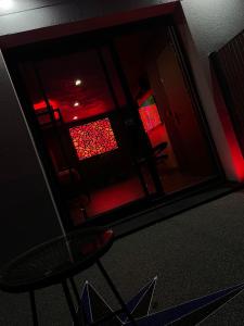 a room with a chair and a window with red lights at Chambre Romantique avec Jacuzzi R in Gruny