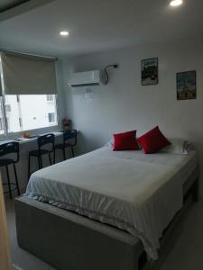 a bedroom with a large bed with two red pillows at Estudio tipo Loft Amoblado en Bocagrande Cartagena 801A in Cartagena de Indias