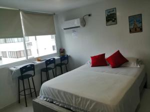 a bedroom with a bed with red pillows and a bar at Estudio tipo Loft Amoblado en Bocagrande Cartagena 801A in Cartagena de Indias