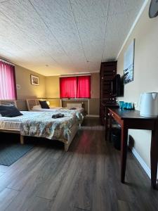 een slaapkamer met een bed, een bureau en rode gordijnen bij Viesnīcas Jolanta apartamenti in Kolberģi