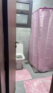 bagno con tenda doccia rosa e servizi igienici di الشاليه الملكى غرفتين وصاله vip منتجع بورتو سعيد a `Ezbet Shalabi el-Rûdi