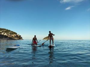 Twee mannen staan op paddleboards in het water. bij B & EAT IL BORGO in Segno