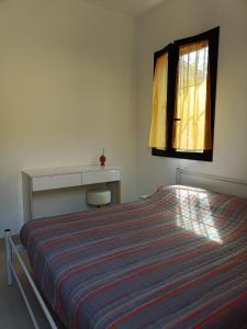 ein Schlafzimmer mit einem Bett mit einer gestreiften Decke und einem Fenster in der Unterkunft A Casa di Amici in Arezzo