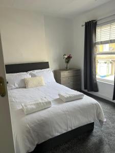 a bedroom with a bed with white sheets and a window at Crown Road Apartment in Kent