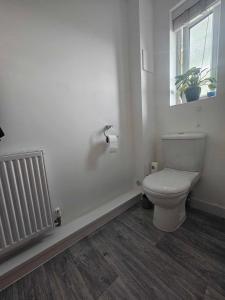 a white bathroom with a toilet and a window at Entire 2 Bedroom House Modern Stylish Luxury in Plymouth