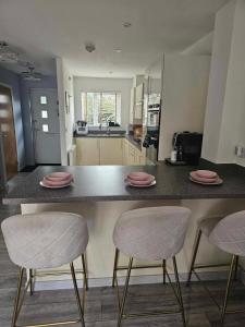 una cocina con 2 sillas y una barra con platos rosados. en Entire 2 Bedroom House Modern Stylish Luxury, en Plymouth