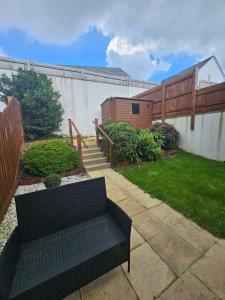 a black bench sitting in a yard next to a fence at Entire 2 Bedroom House Modern Stylish Luxury in Plymouth