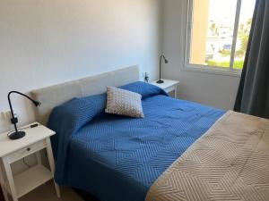 a bedroom with a bed with a blue comforter and a window at Apartamento LOLO in El Médano