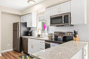 uma cozinha com armários brancos e electrodomésticos de aço inoxidável em Spacious 1BR Flat, Workspace, King Bed em Roseville