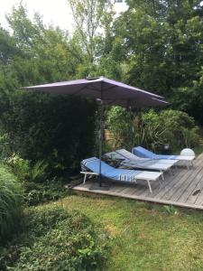Villa 37 في Courrejean: كرسيين ومظلة على سطح خشبي
