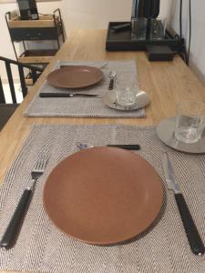 una mesa de madera con platos y utensilios. en Serenity Indepedent Suite near to Disneyland & Paris, en Bussy-Saint-Georges