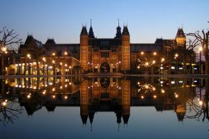 a large building with lights in the water at night at Appartement De Molshoop in Landsmeer