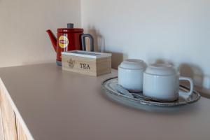 una mesa con dos tazas y una bandeja con una caja de té. en La Terrazza di Emy - affitto turistico, en Arezzo