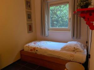 ein kleines Bett in einem Zimmer mit Fenster in der Unterkunft Ruime en comfortabele bungalow aan bosrand in Lage Mierde