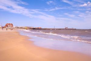 a beach with the ocean and a pier in the background at Gorgeous Gorleston holiday home in Gorleston-on-Sea