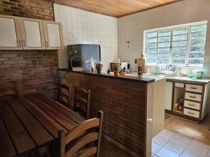 a kitchen with a wooden table and a counter top at Chácara Belvedere.Espaço rural, descanso e lazer in Londrina