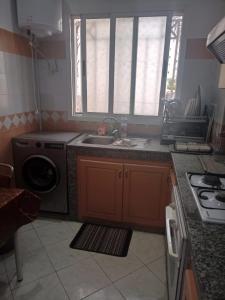 a kitchen with a sink and a washing machine at أكادير حي السلام in Agadir