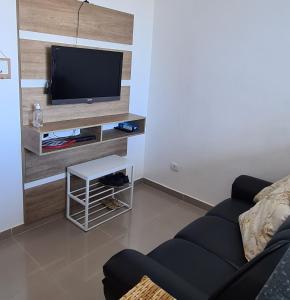 a living room with a couch and a flat screen tv at Apto completo praia Caioba in Matinhos