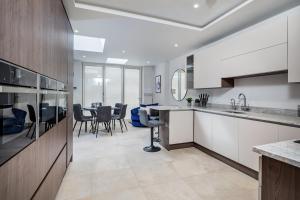 a kitchen with white cabinets and a dining room at Spacious, High Spec & Modern House by Ark SA in Sheffield