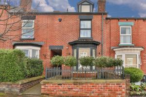 a red brick house with a fence in front of it at Spacious, High Spec & Modern House by Ark SA in Sheffield