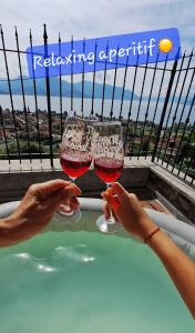 Due persone con bicchieri di vino di fronte a una vasca idromassaggio di Sole & Lago-Lake a Maccagno Superiore
