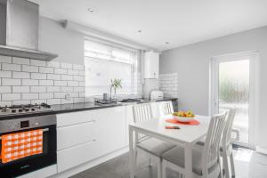 a white kitchen with a white table and chairs at Cloud9 Accommodation in Croydon