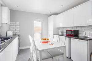 a white kitchen with a bowl of fruit on a table at Cloud9 Accommodation in Croydon