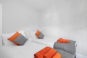 2 camas con almohadas de color naranja y gris en Cloud9 Accommodation en Croydon