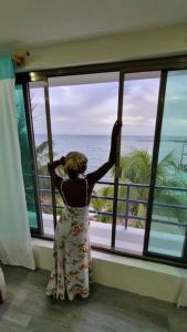 a woman looking out of a window at the ocean at Villa on The Beach Seaside Sunrise Haven 7 bedroom in Cancún