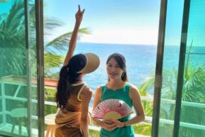 two women standing in front of a window looking at the ocean at Villa on The Beach Seaside Sunrise Haven 7 bedroom in Cancún