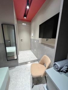 una camera con televisore, sedia e specchio di Mia Suites Porto a Napoli