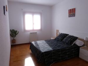 a bedroom with a bed with a black comforter and a window at Eguzkilore - Apartamento luminoso y soleado in Elizondo