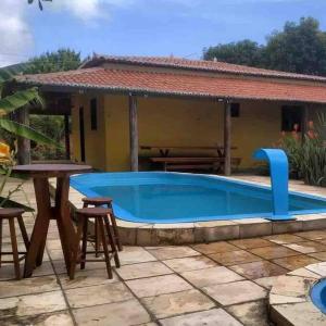 a pool with a table and chairs and a house at Chácara Tantan - Martins RN in Martins