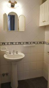 Baño blanco con lavabo y espejo en Clásico y moderno departamento - olivos in 