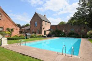 a swimming pool in front of a house at The Cottage, Orgreave Estate in Yoxall