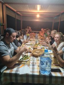 Surf House Desert Point في Tiguert: مجموعة من الناس يجلسون على طاولة لتناول الطعام