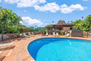 a swimming pool with chairs and a house at Kaanapali Plantation 53 in Lahaina