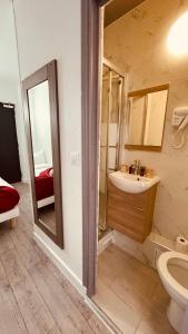 y baño con lavabo, aseo y espejo. en HOTEL LOUVAIN, en París