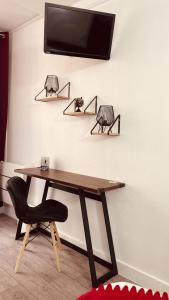 a desk with a chair and a tv on a wall at HOTEL LOUVAIN in Paris +57 photos