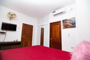 - une chambre avec un lit rouge et une télévision à écran plat dans l'établissement Habitaciones privadas, Casa de Amber, Manta, à Manta