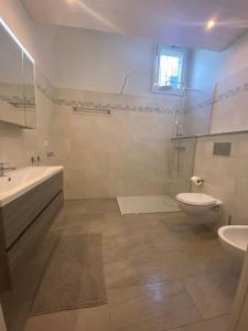 een witte badkamer met een wastafel en een toilet bij Holiday accomodation Coglio in Maggia