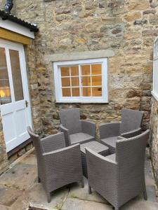 a patio with wicker chairs and a building at Jasmine Cottage in Gilling