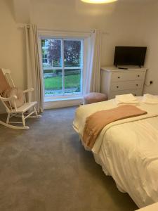 a bedroom with a bed and a chair and a window at Jasmine Cottage in Gilling