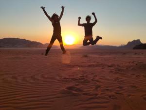 two people jumping in the desert at sunset at Golden Sands Camp in Wadi Rum