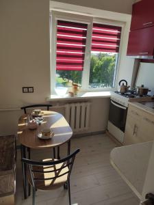 una cucina con tavolo e sedie e due finestre di CHESS Apartment a Ventspils