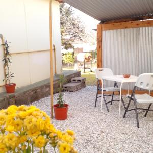 patio z krzesłami i stołem z żółtymi kwiatami w obiekcie casa de ensueño w mieście La Falda